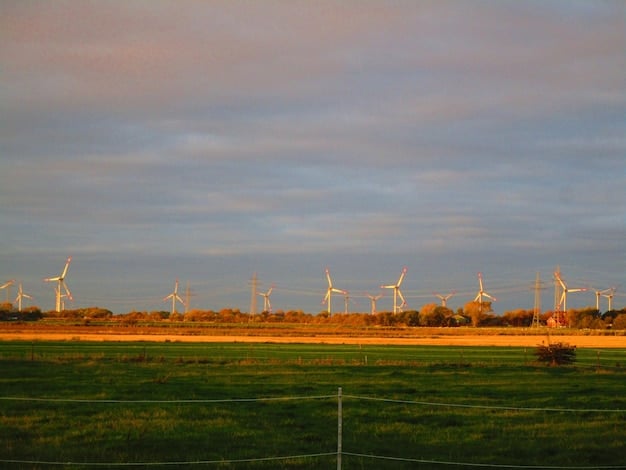 A wide shot of a wind farm at sunset, with rows of wind turbines stretching into the distance. The sky is a mix of orange, pink, and purple hues, creating a dramatic and inspiring scene that highlights the beauty and potential of wind energy.