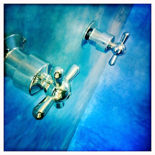 A close-up of a low-flow showerhead and faucet aerator being installed in a modern bathroom, symbolizing water conservation.