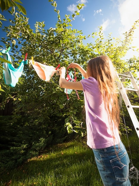 A person using a clothesline to dry clothes outside on a sunny day, highlighting the energy-saving practice and promoting sustainable laundry habits.