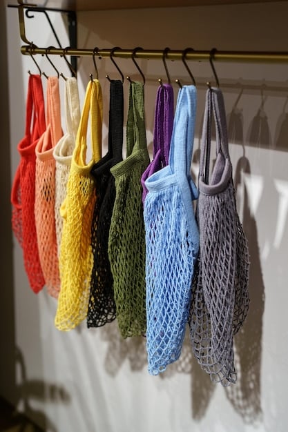 A variety of colorful reusable shopping bags hanging on hooks in a hallway, showcasing different styles and materials.