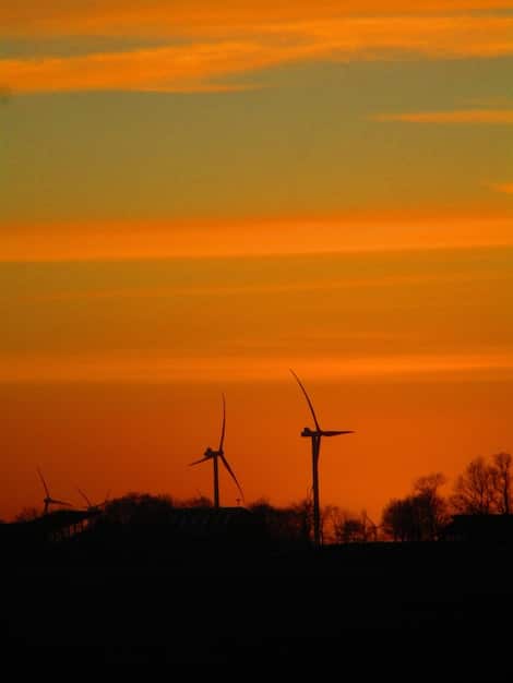 A close-up shot of a wind turbine farm at sunset, highlighting renewable energy and environmental sustainability. The image emphasizes the clean energy aspect of sustainable investing and technological innovation.