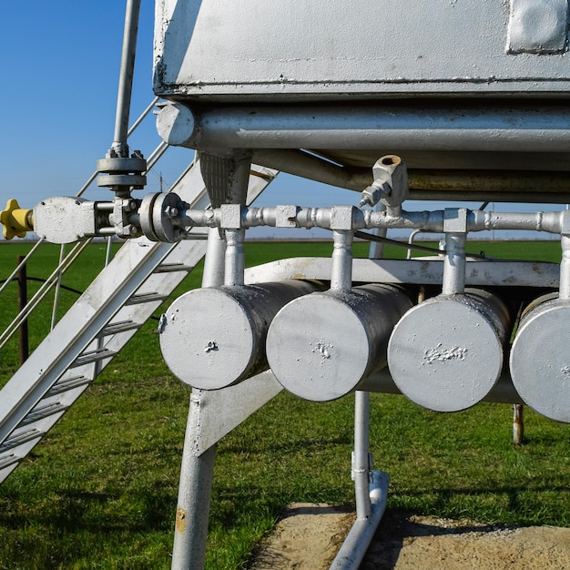 A detailed photograph showcasing a device that captures methane gas being installed at a landfill site in the United States. The device is connected to a network of pipes, with a worker in safety gear overseeing the installation.