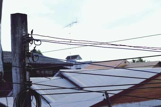 A close-up of a solar panel installation on a residential roof, showcasing the hardware and wiring with a backdrop of suburban homes.