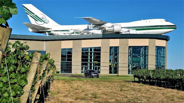 A modern airplane with a partially green fuselage at an airport - conveying it utilizes SAF. A solar farm on the tarmac is powering the aircraft and other nearby facilities.