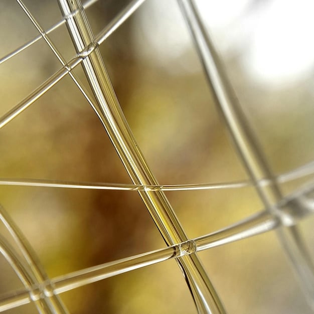 A close-up shot of a semi-transparent perovskite solar cell on a window, allowing diffused sunlight to pass through while generating electricity.