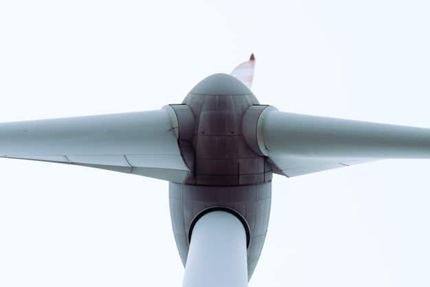 A detailed close-up of a wind turbine blade showing its size relative to a person standing at its base, emphasizing the scale of individual turbines and their potential visual impact.