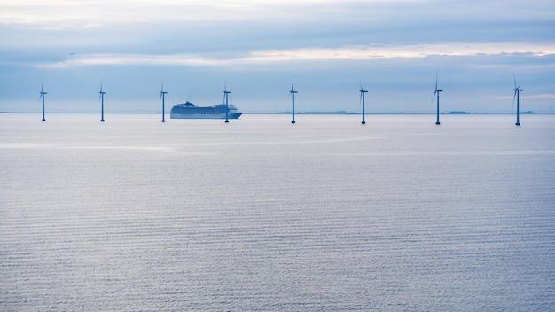 Aerial view of a large offshore wind farm with numerous wind turbines in the ocean under a cloudy sky. The turbines are evenly spaced and stretch far into the horizon.