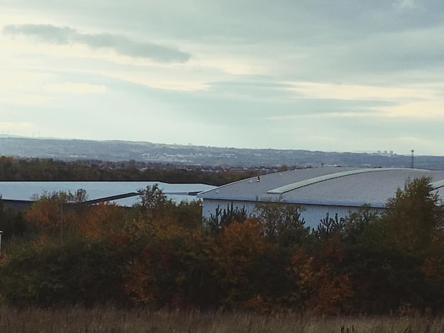 A wide shot of a large floating solar farm on a calm lake, surrounded by green, rolling hills. The panels cover a significant portion of the water's surface, demonstrating the scale of the installation.