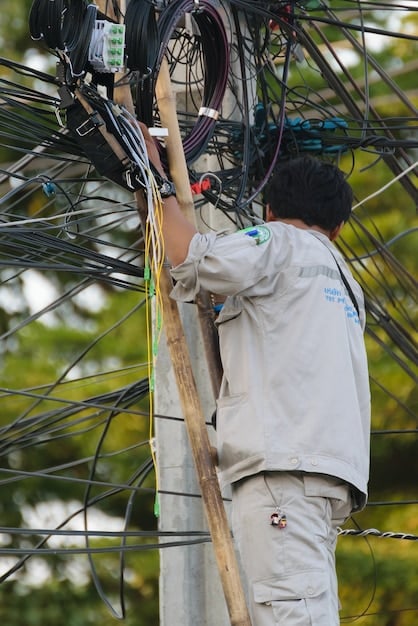 A technician inspecting a complex network of wires and connections at a grid substation. The equipment is related to integrating renewable energy sources, and the scene highlights the technical challenges of modernizing the grid.